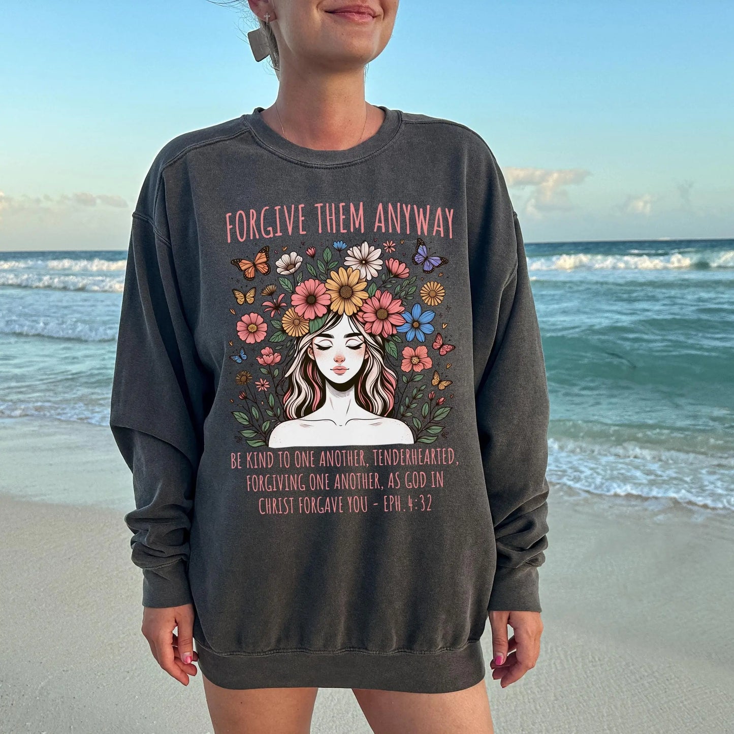 May include: Dark gray sweatshirt featuring a floral illustration of a woman and inspirational text: 'Forgive them anyway.' The text 'Be kind to one another, tenderhearted, forgiving one another, as God in Christ forgave you - Eph 4:32' is also printed on the sweatshirt.