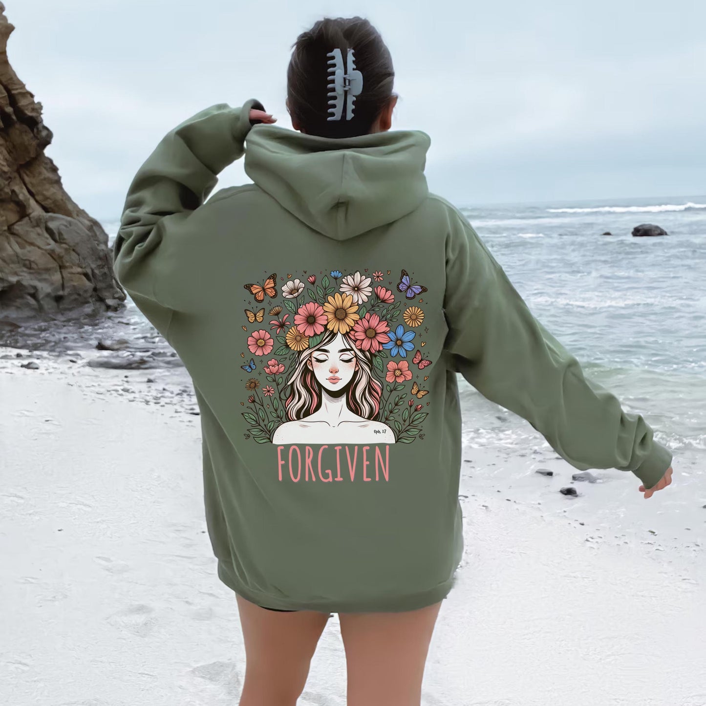 May include: Olive green oversized hoodie sweatshirt featuring a back graphic design of a woman with flowers in her hair and butterflies surrounding her. The word 'FORGIVEN' is printed below the graphic. The hoodie has a drawstring hood and kangaroo pockets.